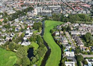 Een dronefoto van de Ringsloot. Links van het water en de dijk bevindt zich de Don Boscostraat, terwijl aan de rechterkant de Meeuwenlaan ligt. Voor ons zien we de Ruishornlaan die het oude dorp verbindt met de Poelpolder. Op de achtergrond sluit de Ringsloot aan op de Greveling. (Foto: Maurice Hoogeveen, 2023.)